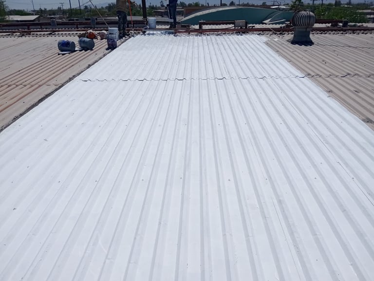 White metal corrugated roof panels on a commercial or industrial building with storage equipment and structures visible in the background