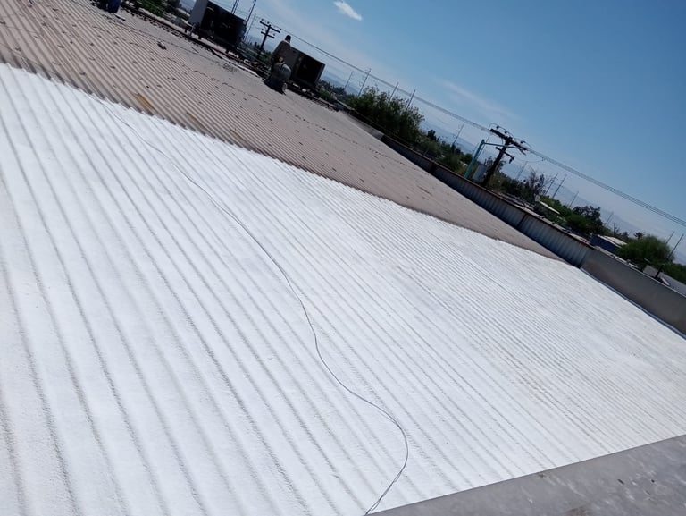 White corrugated metal roof covering a large industrial building with power lines visible in the background under clear blue sky