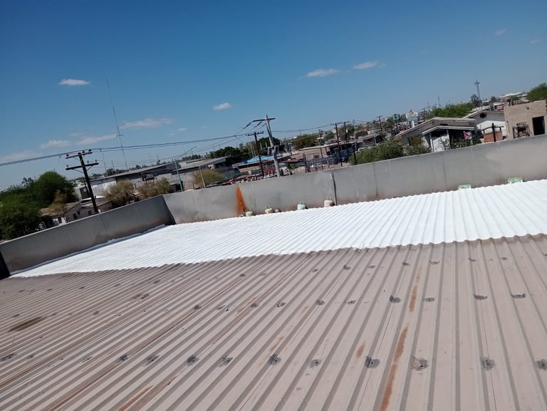 Corrugated metal industrial roof with urban buildings and clear blue sky in background